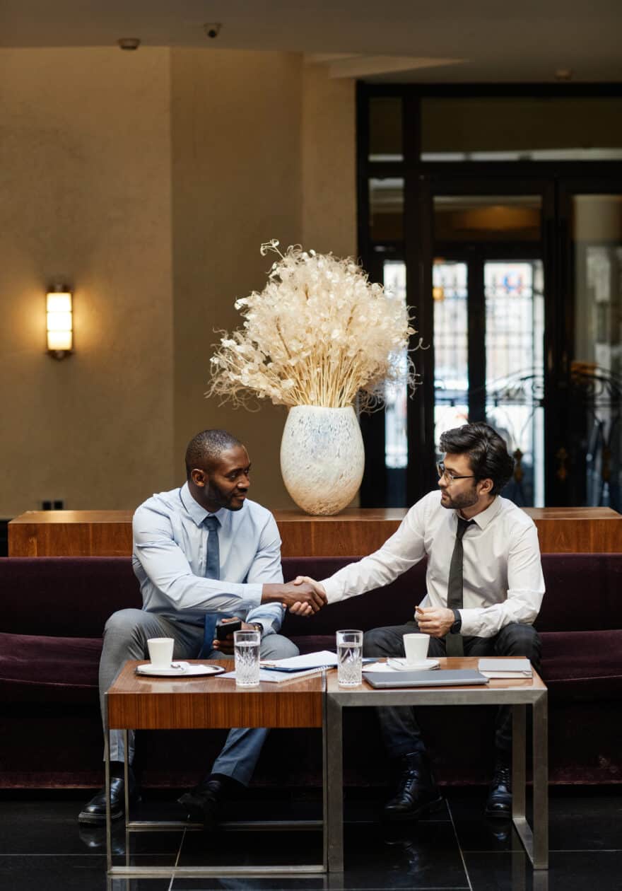 Two Businessmen Shaking Hands in Hotel Lobby